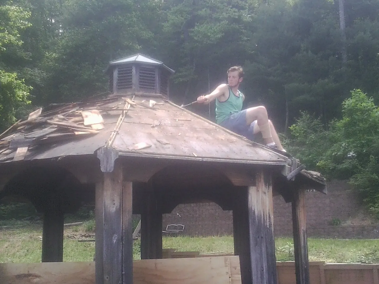 Tearing the old roof off a wooden gazebo before new shakes in Howe