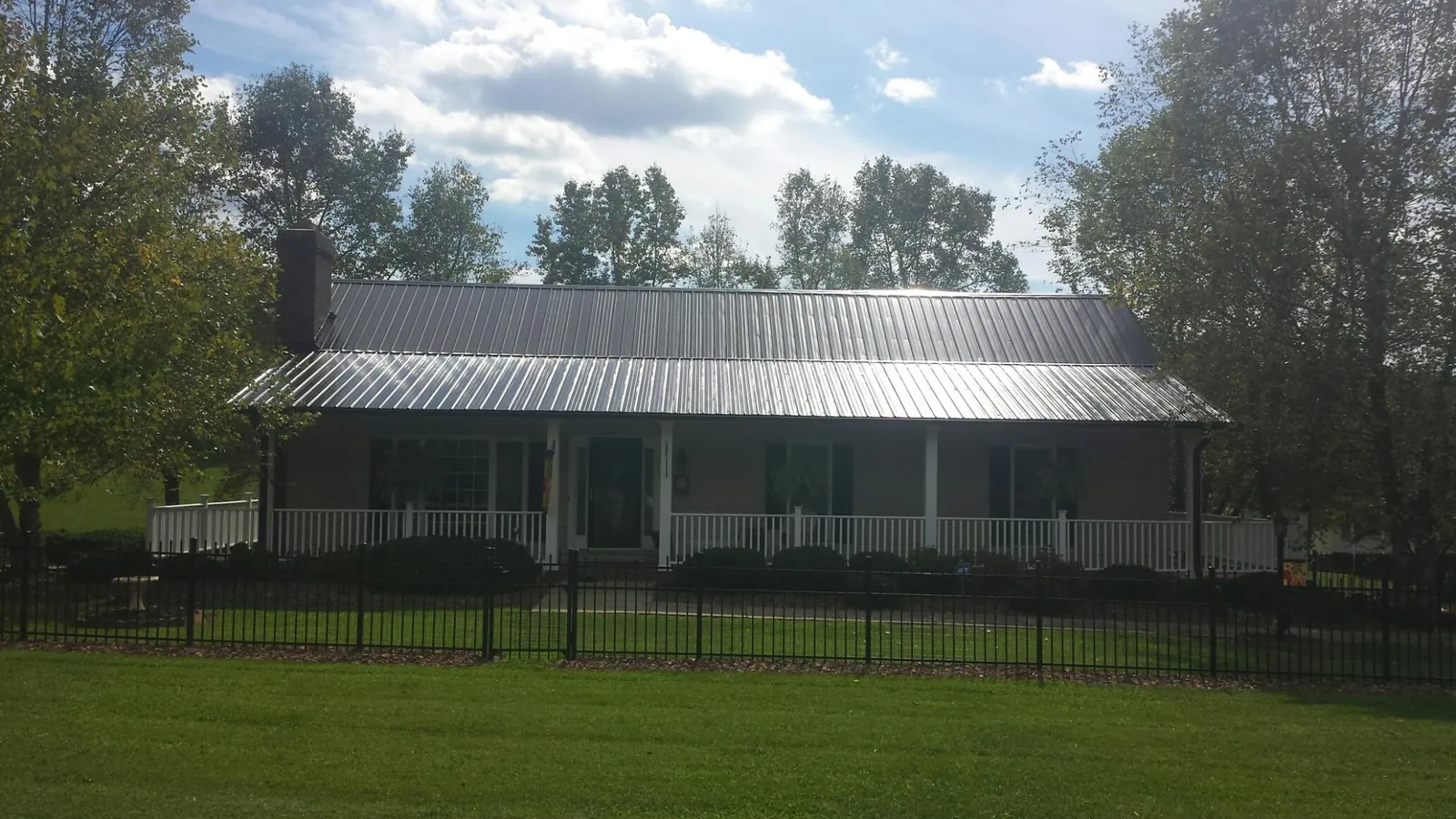 Gray metal roof on a brick ranch with a full width front porch — Gutter Guard Installation work by our crew in Howe